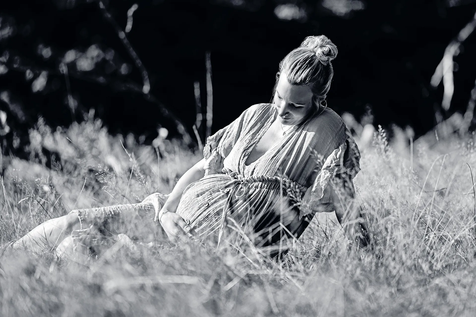 Schwangere Frau sitzend in einer Wiese