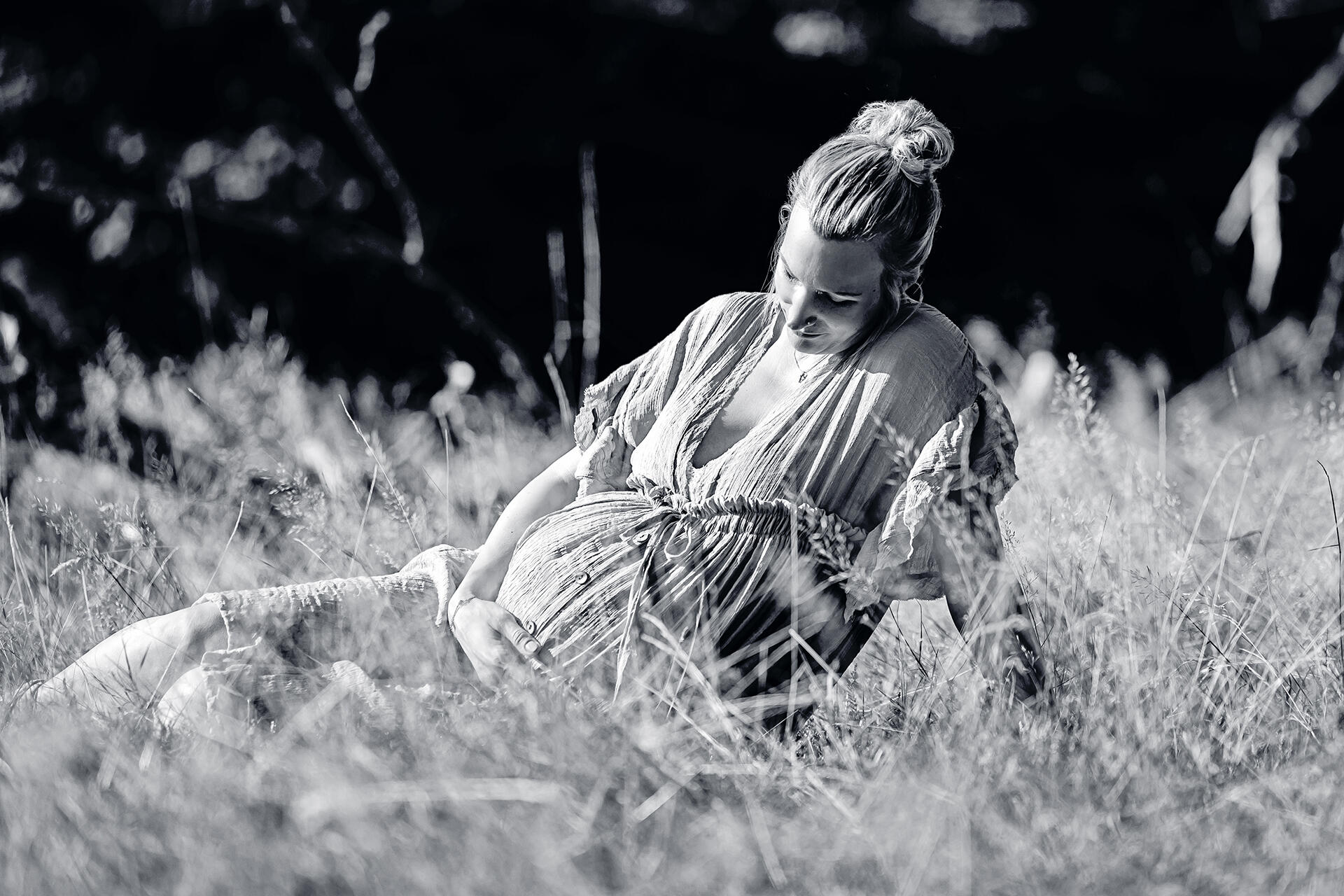 Schwangere Frau sitzend in einer Wiese